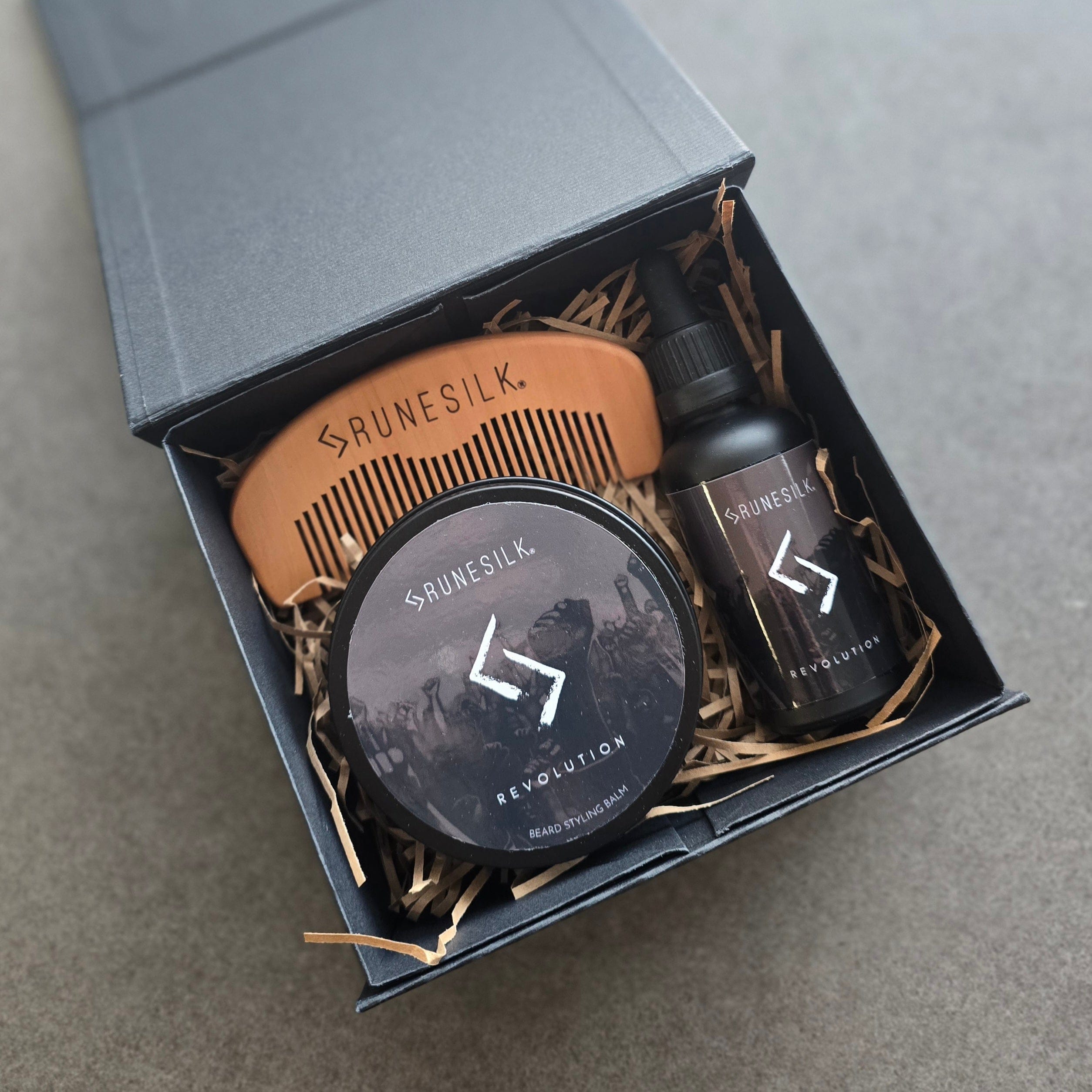 Brunesilk grooming products including a comb, tin and bottle in a box on a gray background
